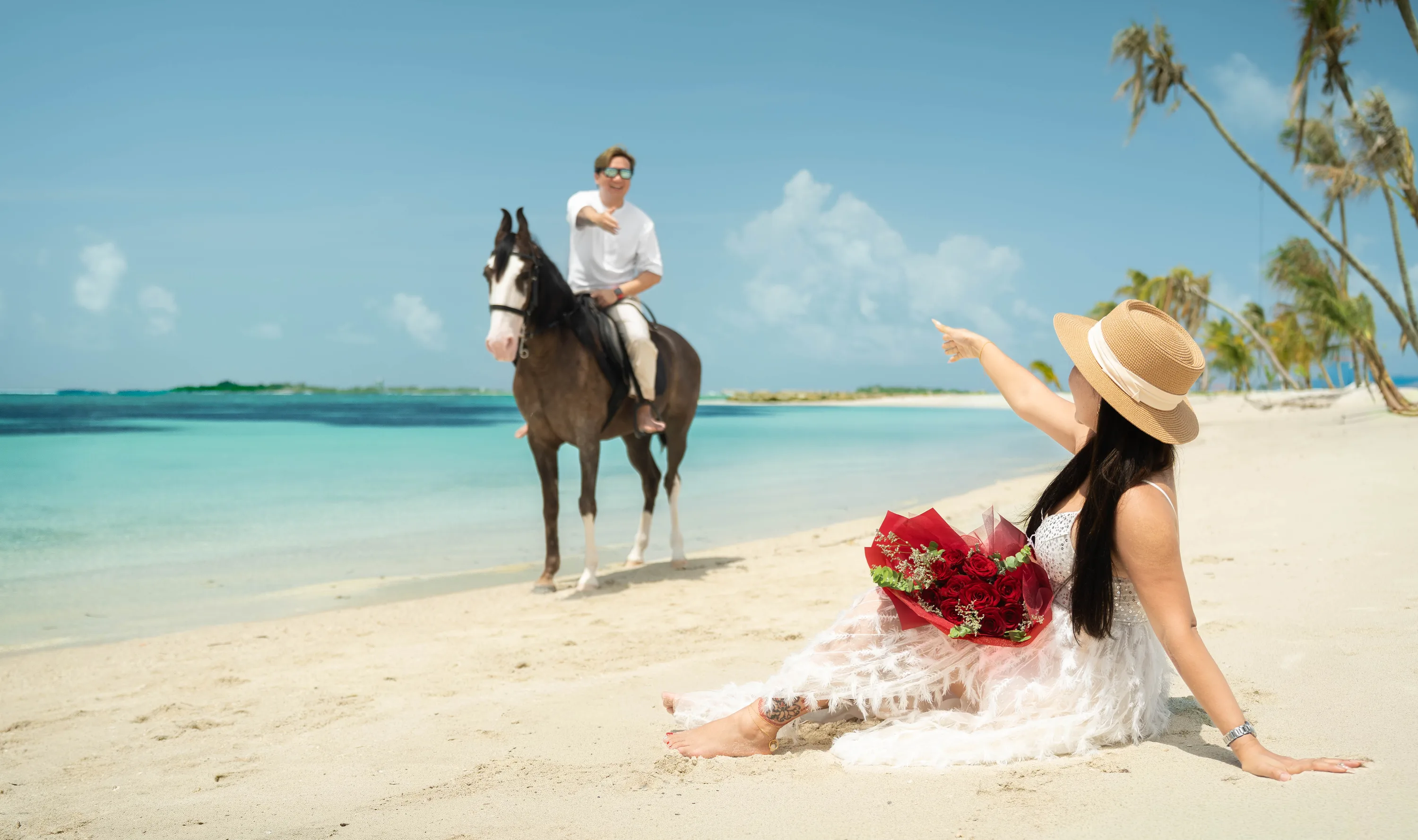 Ein Reiter am Strand und ein Gast mit Rosen unter den Palmen